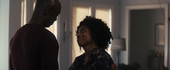 Movie still from “The Domestics” (2018), directed by Mike P. Nelson – A woman with curly black hair standing next to a man; Medium shot, Over the shoulder angle