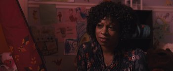 Movie still from “The Domestics” (2018), directed by Mike P. Nelson – A woman sitting in front of a wall with drawings on the wall; Close Up shot, Over the shoulder angle