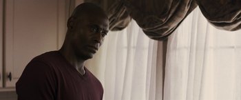 Movie still from “The Domestics” (2018), directed by Mike P. Nelson – A man standing in front of a window with curtains; Close Up shot, Over the shoulder angle