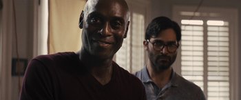Movie still from “The Domestics” (2018), directed by Mike P. Nelson – A man smiles while standing next to another man; Close Up shot, Over the shoulder angle