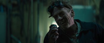 Movie still from “The Domestics” (2018), directed by Mike P. Nelson – An older man wearing goggles and holding a cell phone; Close Up shot, Low angle