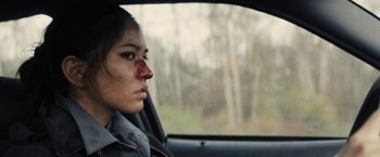 Movie still from “The Domestics” (2018), directed by Mike P. Nelson – A woman with a bruised face riding in a car; Close Up shot, Over the shoulder angle