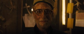 Movie still from “The Domestics” (2018), directed by Mike P. Nelson – An older man wearing glasses and a hat; Close Up shot, Low angle
