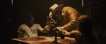 Movie still from “The Domestics” (2018), directed by Mike P. Nelson – A man in a cowboy hat and gloves working on a machine; Medium shot, High angle