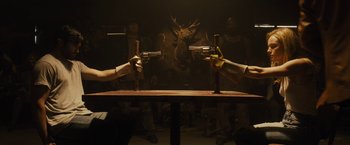 Movie still from “The Domestics” (2018), directed by Mike P. Nelson – A couple of people that are holding guns in their hands; Medium shot, Over the shoulder angle