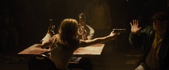 Movie still from “The Domestics” (2018), directed by Mike P. Nelson – A woman holding a gun in a room with a man; Medium shot, Over the shoulder angle