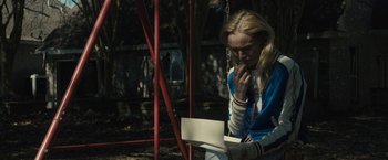 Movie still from “The Domestics” (2018), directed by Mike P. Nelson – A woman sitting on a swing talking on the phone; Medium shot, Over the shoulder angle