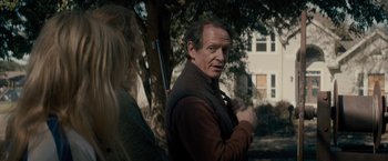 Movie still from “The Domestics” (2018), directed by Mike P. Nelson – A man holding a rifle in front of a woman; Medium shot, Over the shoulder angle