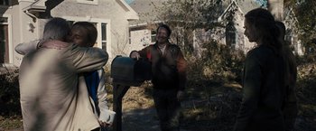 Movie still from “The Domestics” (2018), directed by Mike P. Nelson – A man standing next to a mailbox in a yard; Medium shot, Over the shoulder angle