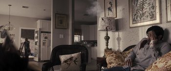 Movie still from “The Domestics” (2018), directed by Mike P. Nelson – A living room with a chair and a lamp; Medium shot, High angle