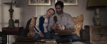 Movie still from “The Domestics” (2018), directed by Mike P. Nelson – A man and a woman sitting on a couch; Medium shot, High angle