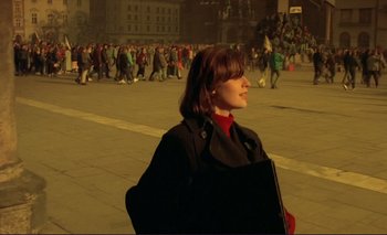 Movie still from “The Double Life of Véronique” (1991), directed by Krzysztof Kieslowski – A woman is standing in the middle of a crowded street; Medium shot, High angle
