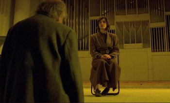 Movie still from “The Double Life of Véronique” (1991), directed by Krzysztof Kieslowski – A woman sitting on a chair in front of a man; Wide shot, Low angle