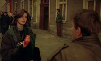 Movie still from “The Double Life of Véronique” (1991), directed by Krzysztof Kieslowski – A woman holding a bag in front of a man; Medium shot, Over the shoulder angle