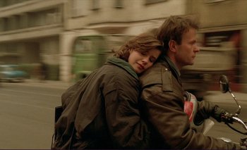 Movie still from “The Double Life of Véronique” (1991), directed by Krzysztof Kieslowski – A man and a woman sitting next to each other on a street; Medium shot, Low angle