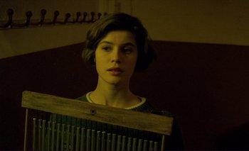 Movie still from “The Double Life of Véronique” (1991), directed by Krzysztof Kieslowski – A young woman holding an old wooden loom; Close Up shot, Low angle