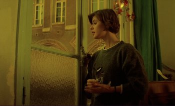 Movie still from “The Double Life of Véronique” (1991), directed by Krzysztof Kieslowski – A woman standing in front of a glass window; Medium shot, Low angle