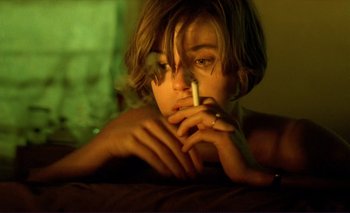 Movie still from “The Double Life of Véronique” (1991), directed by Krzysztof Kieslowski – A woman is smoking a cigarette in a dark room; Close Up shot, High angle