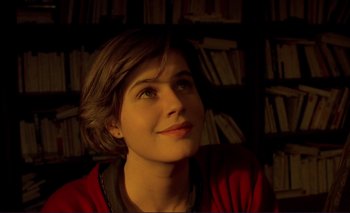 Movie still from “The Double Life of Véronique” (1991), directed by Krzysztof Kieslowski – A woman sitting in front of a book shelf; Close Up shot, Low angle
