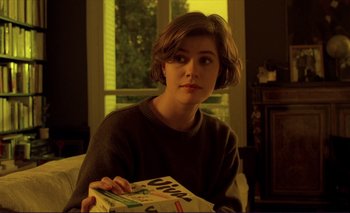 Movie still from “The Double Life of Véronique” (1991), directed by Krzysztof Kieslowski – A woman sitting on a couch holding a box of cereal; Close Up shot, Low angle