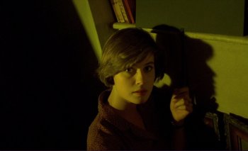 Movie still from “The Double Life of Véronique” (1991), directed by Krzysztof Kieslowski – A young woman is looking at the camera in a dark room; Close Up shot, Overhead angle