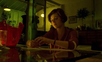Movie still from “The Double Life of Véronique” (1991), directed by Krzysztof Kieslowski – A woman sitting at a glass table in a room; Medium shot, Low angle