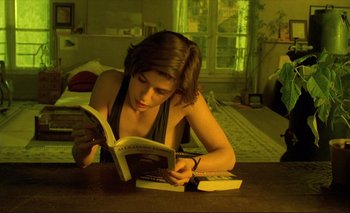 Movie still from “The Double Life of Véronique” (1991), directed by Krzysztof Kieslowski – A woman is reading a book on a table; Medium shot, High angle