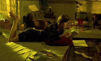 Movie still from “The Double Life of Véronique” (1991), directed by Krzysztof Kieslowski – A woman laying on the floor reading a book; Wide shot, High angle