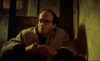 Movie still from “The Double Life of Véronique” (1991), directed by Krzysztof Kieslowski – A man sitting on top of a couch in a living room; Close Up shot, High angle