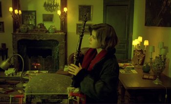 Movie still from “The Double Life of Véronique” (1991), directed by Krzysztof Kieslowski – A woman is holding an instrument in a living room; Wide shot, Over the shoulder angle