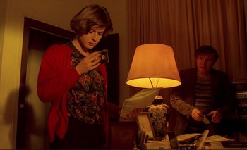 Movie still from “The Double Life of Véronique” (1991), directed by Krzysztof Kieslowski – A woman looking at a camera while a man looks at a lamp; Medium shot, Over the shoulder angle