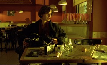 Movie still from “The Double Life of Véronique” (1991), directed by Krzysztof Kieslowski – A woman sitting at a table in a restaurant; Medium shot, Low angle