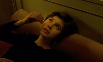 Movie still from “The Double Life of Véronique” (1991), directed by Krzysztof Kieslowski – A woman laying on a couch listening to music with headphones; Close Up shot, Overhead angle