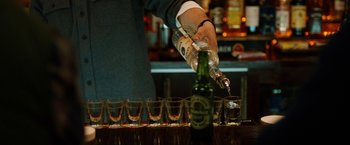 Movie still from “The Drop” (2014), directed by Michaël R. Roskam – A person pouring a drink into a row of shot glasses; Extreme Close Up shot, High angle