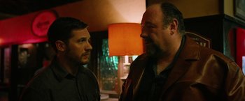 Movie still from “The Drop” (2014), directed by Michaël R. Roskam – Two men standing next to each other in a room; Close Up shot, Over the shoulder angle