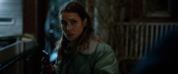 Movie still from “The Drop” (2014), directed by Michaël R. Roskam – A woman in a green jacket standing next to a tree; Close Up shot, Over the shoulder angle