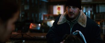 Movie still from “The Drop” (2014), directed by Michaël R. Roskam – A man in a black jacket and a black hat; Close Up shot, Over the shoulder angle