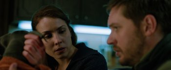 Movie still from “The Drop” (2014), directed by Michaël R. Roskam – A woman and a man sitting next to each other in a room; Close Up shot, Over the shoulder angle