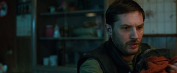 Movie still from “The Drop” (2014), directed by Michaël R. Roskam – A person sitting in a room; Close Up shot, Over the shoulder angle