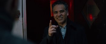 Movie still from “The Drop” (2014), directed by Michaël R. Roskam – A man in a black jacket is smiling and pointing to the camera; Close Up shot, Over the shoulder angle
