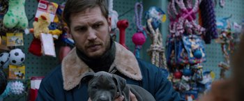 Movie still from “The Drop” (2014), directed by Michaël R. Roskam – A man holding a dog in his arms; Close Up shot, Over the shoulder angle