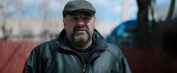 Movie still from “The Drop” (2014), directed by Michaël R. Roskam – A person wearing a jacket and a hat; Close Up shot, Over the shoulder angle