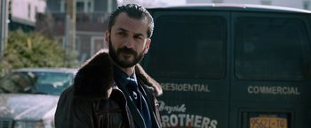 Movie still from “The Drop” (2014), directed by Michaël R. Roskam – A man with a beard wearing a leather jacket; Close Up shot, Over the shoulder angle