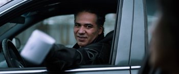 Movie still from “The Drop” (2014), directed by Michaël R. Roskam – A man sitting in the drivers seat of a car; Close Up shot, Low angle