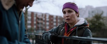 Movie still from “The Drop” (2014), directed by Michaël R. Roskam – A woman wearing a purple headband is standing by a railing; Close Up shot, Over the shoulder angle
