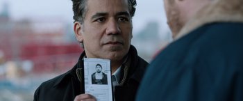 Movie still from “The Drop” (2014), directed by Michaël R. Roskam – A man holding up a picture of a man; Close Up shot, Over the shoulder angle