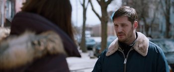 Movie still from “The Drop” (2014), directed by Michaël R. Roskam – A man in a blue jacket standing on the sidewalk; Close Up shot, Over the shoulder angle