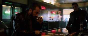 Movie still from “The Drop” (2014), directed by Michaël R. Roskam – A man sitting at a bar drinking a beverage; Medium shot, Over the shoulder angle