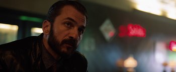 Movie still from “The Drop” (2014), directed by Michaël R. Roskam – A person wearing a suit and tie; Close Up shot, Over the shoulder angle