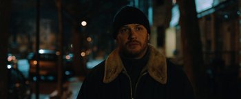 Movie still from “The Drop” (2014), directed by Michaël R. Roskam – A person wearing a jacket and a hat; Close Up shot, Over the shoulder angle